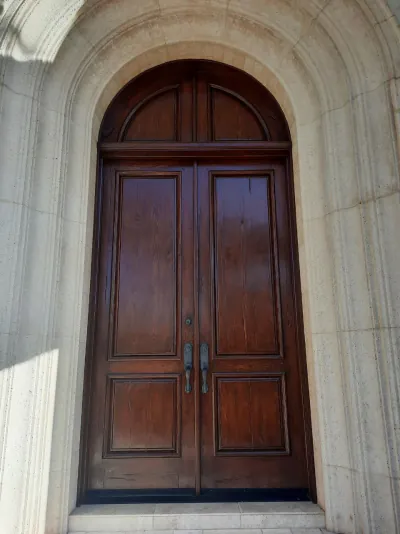 Arched mahogany double entry doors in a stone surround