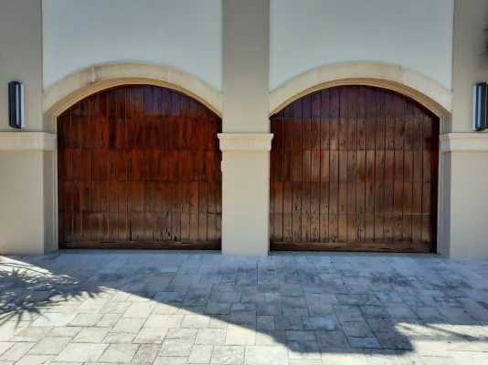 Wooden garage doors refinished in dark mahogany to match the front entry