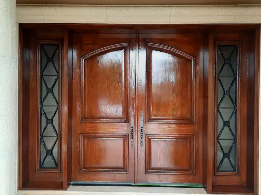 Mahogany double entry doors with matching sidelights and wrought-iron glass inserts